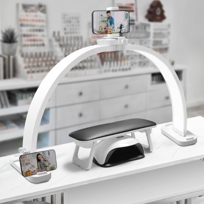 Aparelho branco com suporte para telemóvel e banco acolchoado preto numa mesa