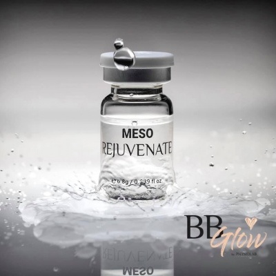 Frasco de vidro com produto MESO REJUVENATE sobre superfície molhada com gotas de água