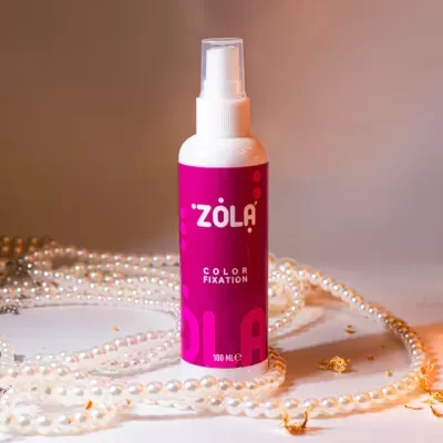Frasco de spray ZÔLA Color Fixation rosa com colares de pérolas em fundo branco