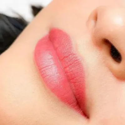 Lábios femininos com batom vermelho rosa mate em close-up