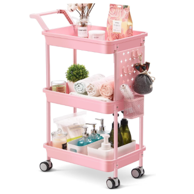 Carrinho de armazenamento rosa com três prateleiras e rodízios contendo produtos de higiene e decoração