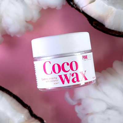 Frasco de Coco Wax para sobrancelhas com aroma de coco, entre cocos e vapor num fundo rosa