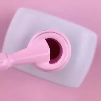 Frasco de verniz cor-de-rosa aberto com pincel embebido