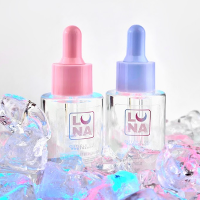 Frascos transparentes com conta-gotas rosa e azul sobre cubos de gelo coloridos