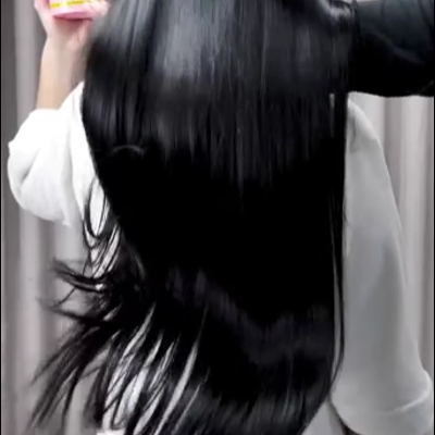 Pessoa de cabelo preto longo segurando embalagem rosa de produto capilar com texto