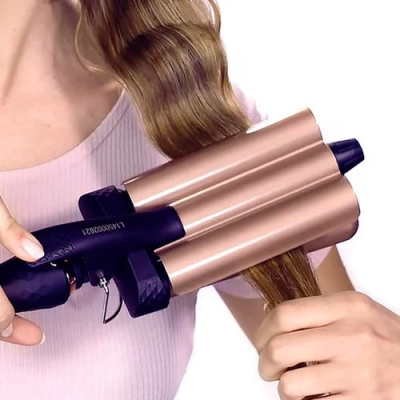 Aparelho para ondular cabelo com três cilindros cor cobre e preto em uso