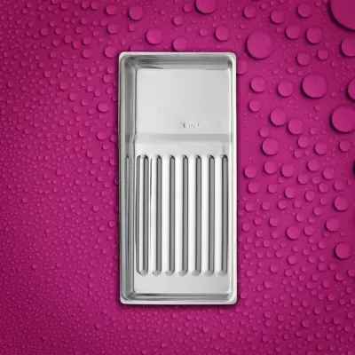 Tabuleiro metálico prateado com ranhuras sobre fundo rosa com gotas