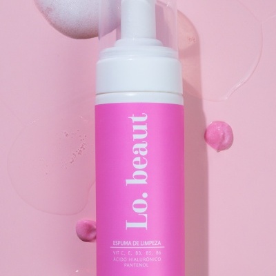 Frasco com espuma de limpeza Lo.beaut em fundo rosa com espuma e gotas