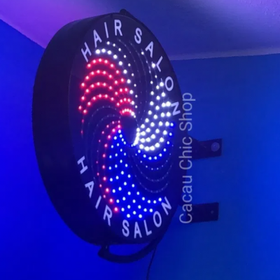 Letreiro luminoso redondo HAIR SALON com LEDs coloridos numa parede azul