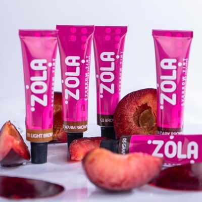 Tubos cor-de-rosa de tinta para sobrancelhas Zola com fatias de ameixa ao redor