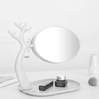 Espelho oval branco com suporte em forma de árvore e base redonda com produtos de beleza.