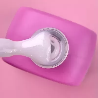 Pincel de unhas com verniz branco cintilante em superfície rosa