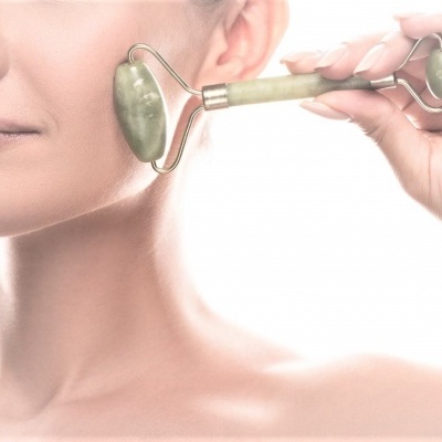 Mulher a usar rolo de massagem facial em pedra verde no rosto