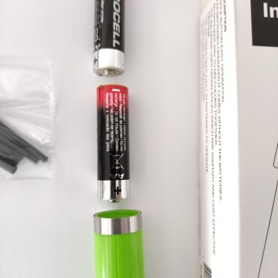 Bateria AA AEROCELL e um dispositivo verde aberto, junto a uma caixa branca com texto