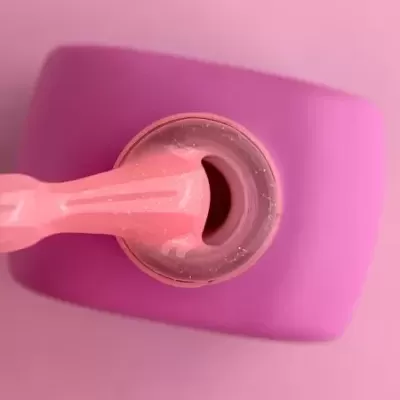 Frasco de verniz de unhas rosa com pincel e textura brilhante