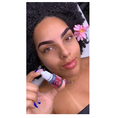 Mulher segurando frasco de produto cosmético com rótulo vermelho