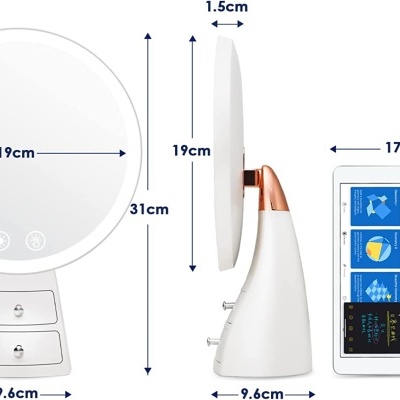 Espelho de maquilhagem com luzes LED e gavetões brancos, ao lado de um tablet.