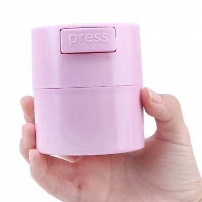 Frasco rosa claro com botão 'press' segurado por mão