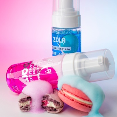 Duas embalagens de espuma de limpeza Zola, uma azul e outra rosa, com dois macarons cobertos por espuma rosa e azul
