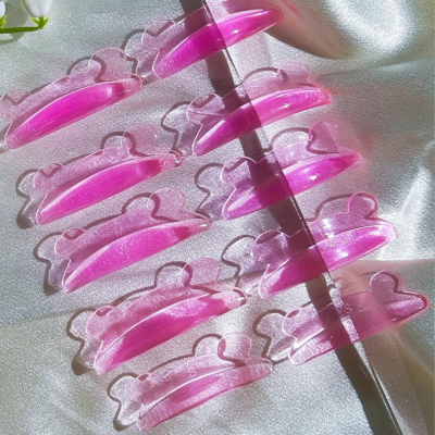 Garras de cabelo rosa transparentes sobre tecido acetinado branco