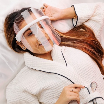 Mulher deitada com máscara facial transparente e roupão branco