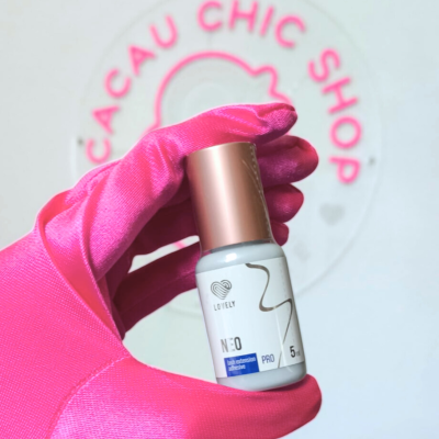 Frasco pequeno branco com tampa dourada rosada segurado por mão com luva rosa