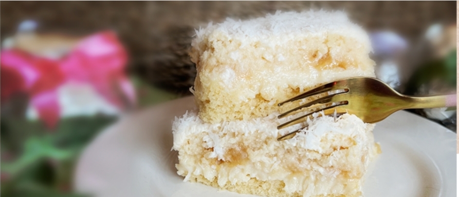 Dois pedaços de bolo branco com garfo dourado num prato branco