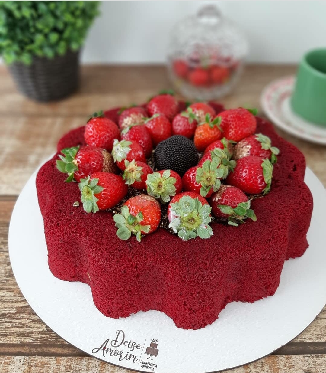 bolo vermelho decorado com morangos e amora sobre base branca com texto