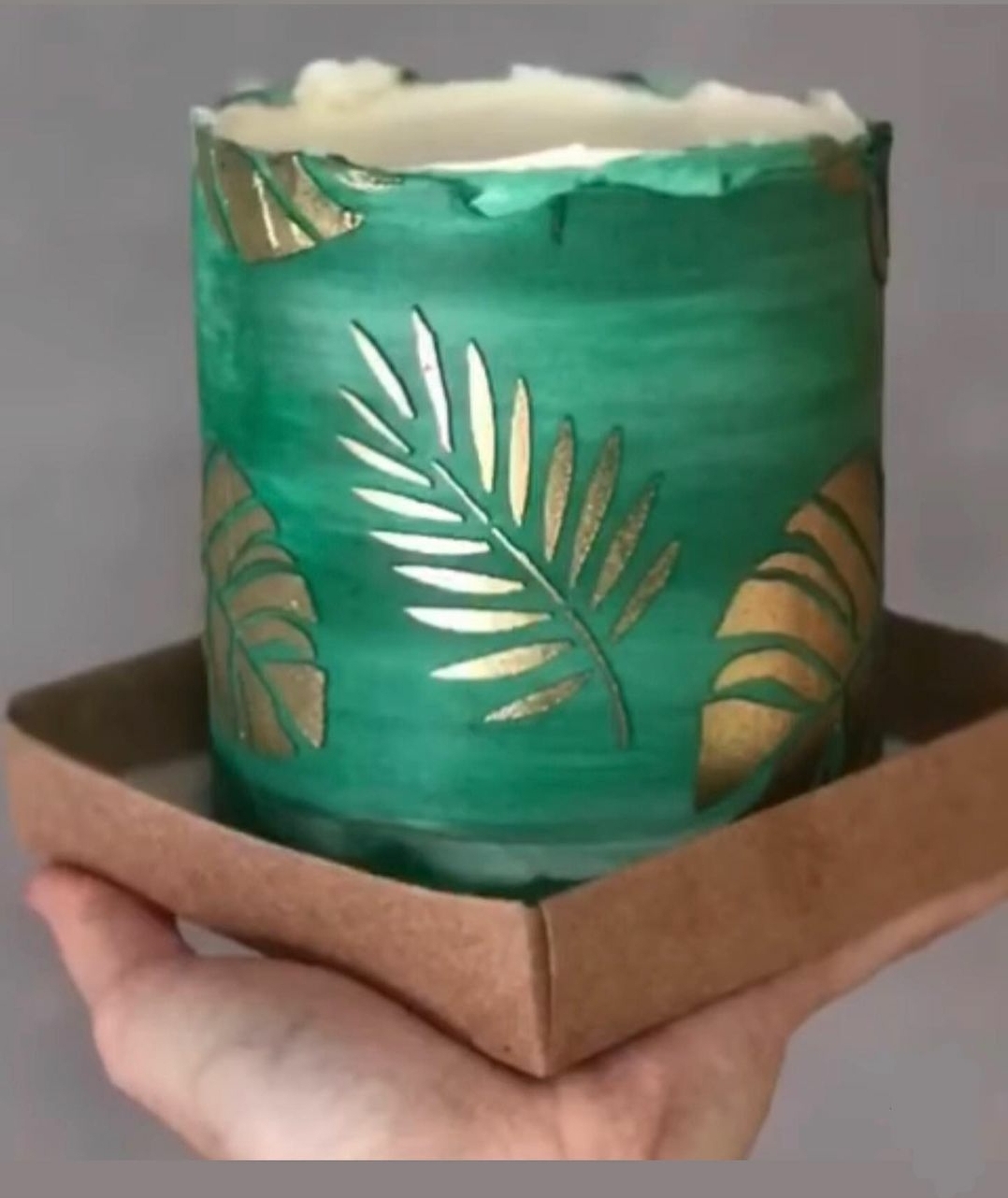 Vela decorativa verde com folhas douradas em suporte castanho