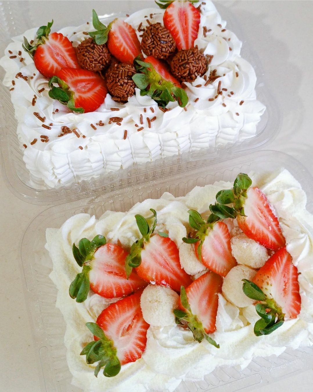 Sobremesas com morangos e chantilly em embalagens plásticas transparentes