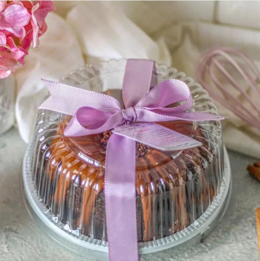 Bolo decorado embalado com fita lilás e tampa plástica transparente