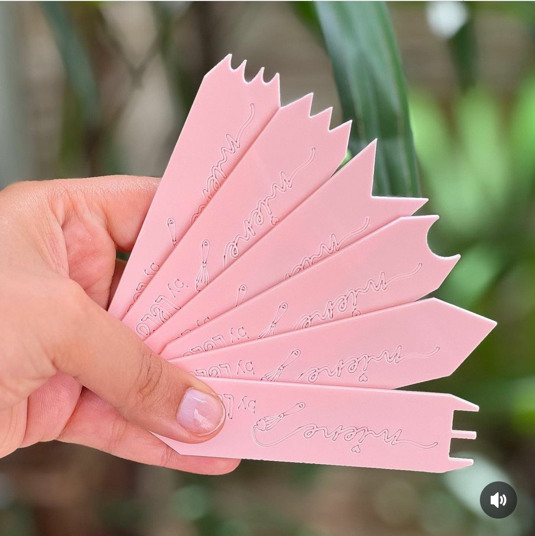 Sete tiras plásticas rosa com inscrições em relevo, seguradas por uma mão