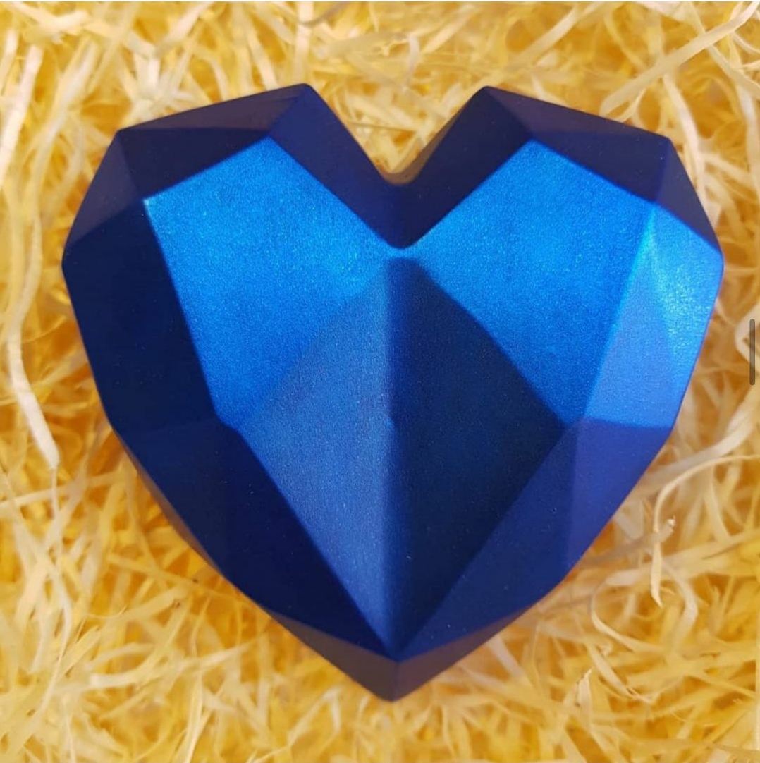 Coração azul facetado com acabamento metálico sobre palha amarela