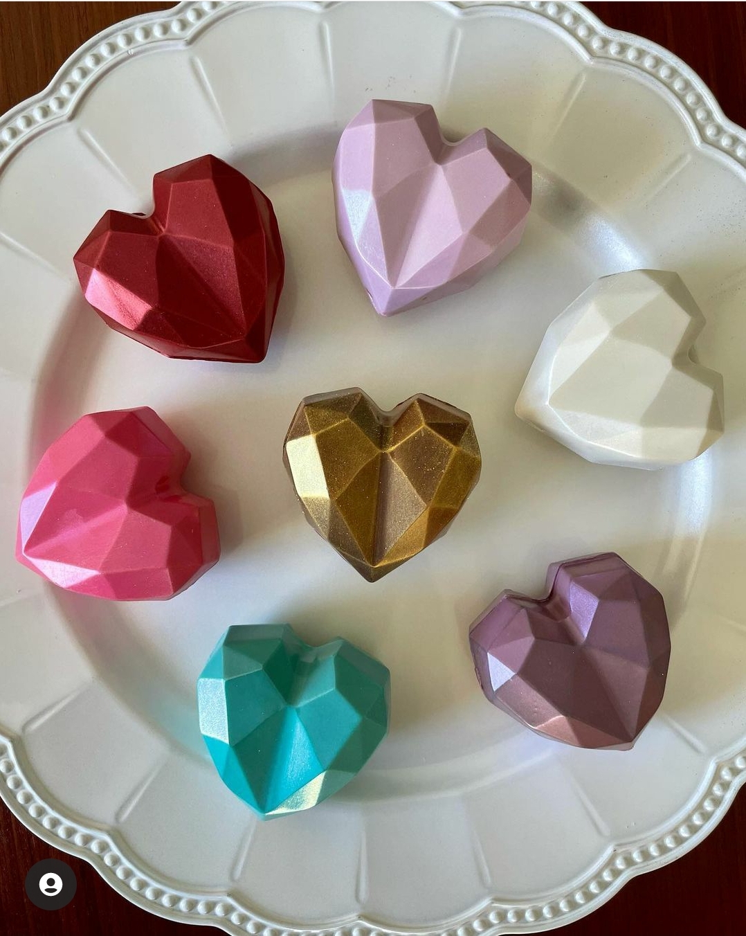 Sete corações de chocolate coloridos facetados num prato branco