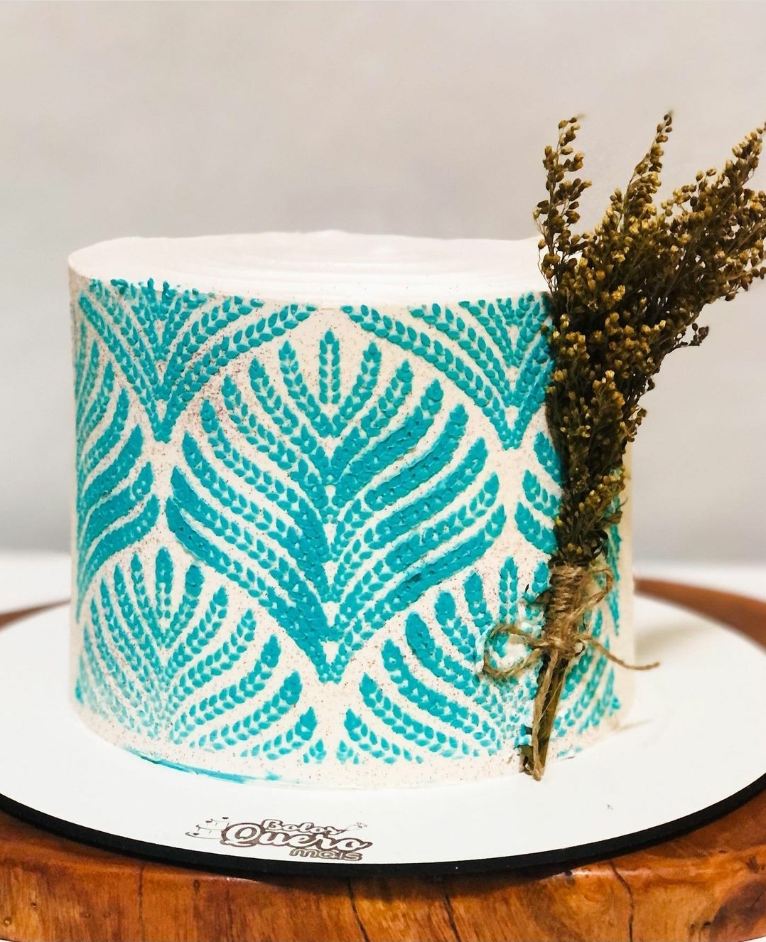 Bolo decorado com padrão turquesa e ramo seco amarrado
