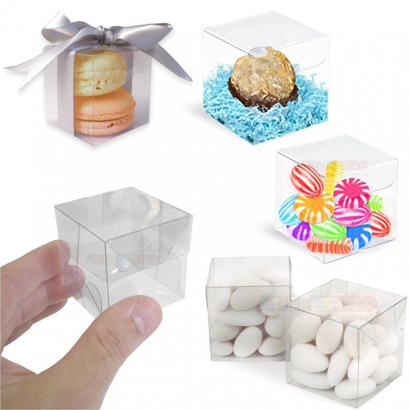 Caixas plásticas transparentes cubo para doces com diferentes conteúdos e uma caixa vazia segurada por uma mão.