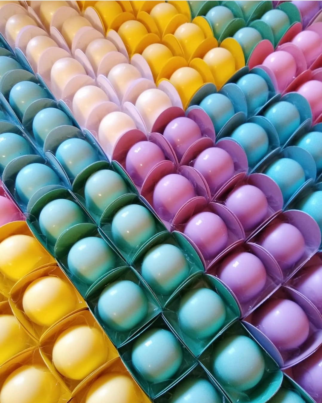 Ovos coloridos organizados em embalagens plásticas alinhadas por cor