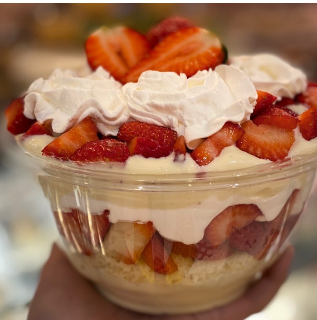 Taça transparente com sobremesa de creme, morangos e chantili