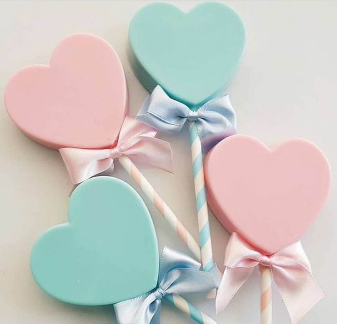 Pirulitos em forma de coração cor-de-rosa e azul claro com fitas de cetim