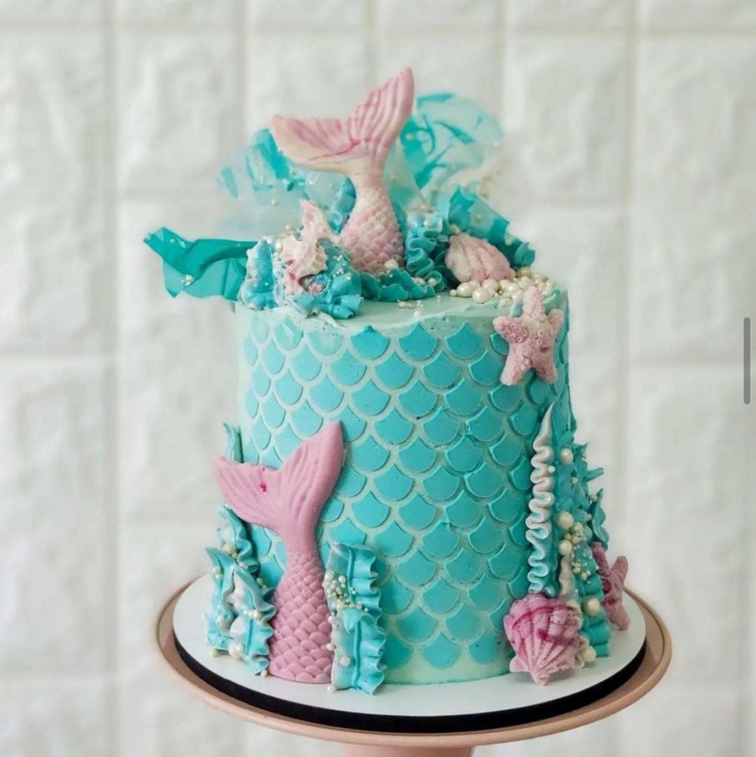 Bolo decorado azul com tema de sereia e detalhes em rosa, conchas e estrelas do mar