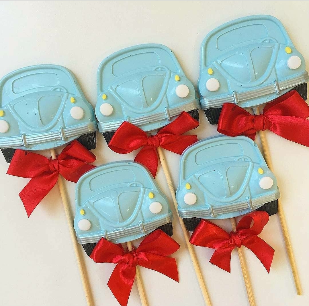 Pirulitos em formato de carrinho azul claro com laços vermelhos