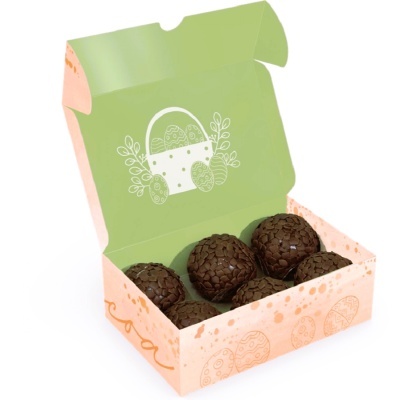 Caixa aberta com cinco brigadeiros cobertos por granulados dentro.