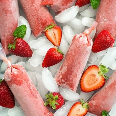 Gelados de morango em saquetas plásticas sobre gelo com morangos frescos e hortelã