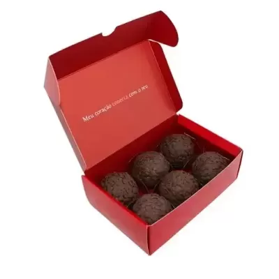 Caixa vermelha aberta com seis bombons de chocolate escuro