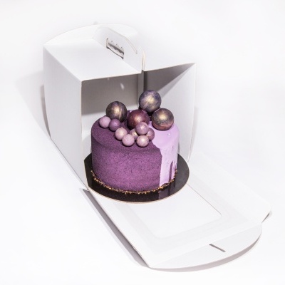 Bolo roxo decorado com esferas dentro de caixa branca