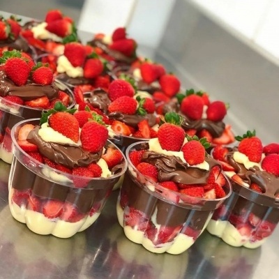 Copos transparentes com sobremesa de creme, chocolate e morangos frescos em camadas