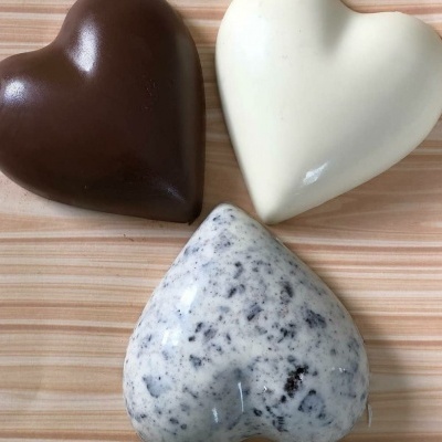 Três corações de chocolate em branco, castanho e branco com pedaços pretos