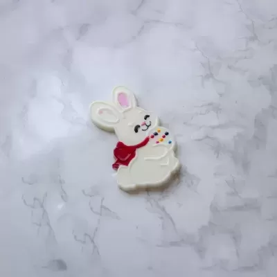 Broche coelho branco com cachecol vermelho sobre fundo marmoreado cinzento