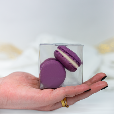 Duas macarons lilás em embalagem transparente na mão feminina