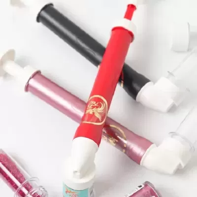 Aplicadores tipo seringa com glitter rosa e frascos pequenos de glitter em fundo branco